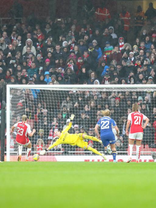 Spielszene: Die Torhüterin von Chelsea streckt sich nach einem Ball, der auf's Tor geht. Im Hintergrund eine vollbesetzte Tribüne.