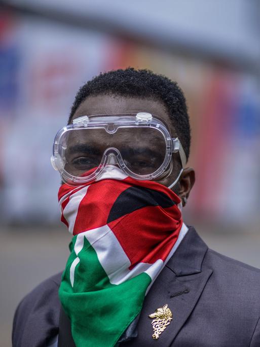 Ein Demonstrant trägt eine Schutzbrille und eine kenianische Flagge vor Mund und Nase.