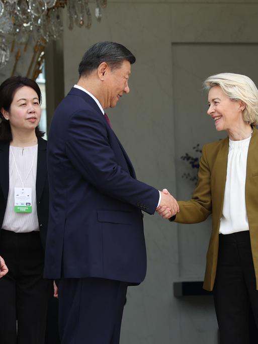 Der chinesische Präsident Xi Jingping und EU-Kommisionspräsidentin Ursula von der Leyen geben sich vor dem Élysée Palast in Paris die Hand. Links von ihnen ist Frankreichs Präsident Emmanuel Macron.