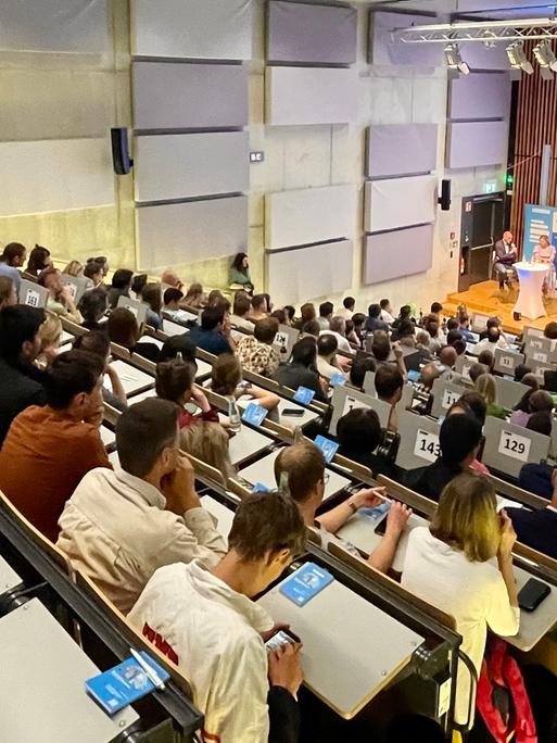 Knapp 200 Menschen lauschen einer Live-Aufzeichnung des Dlf Politkpodcast in einem Hörsaal der Universität Duisburg-Essen