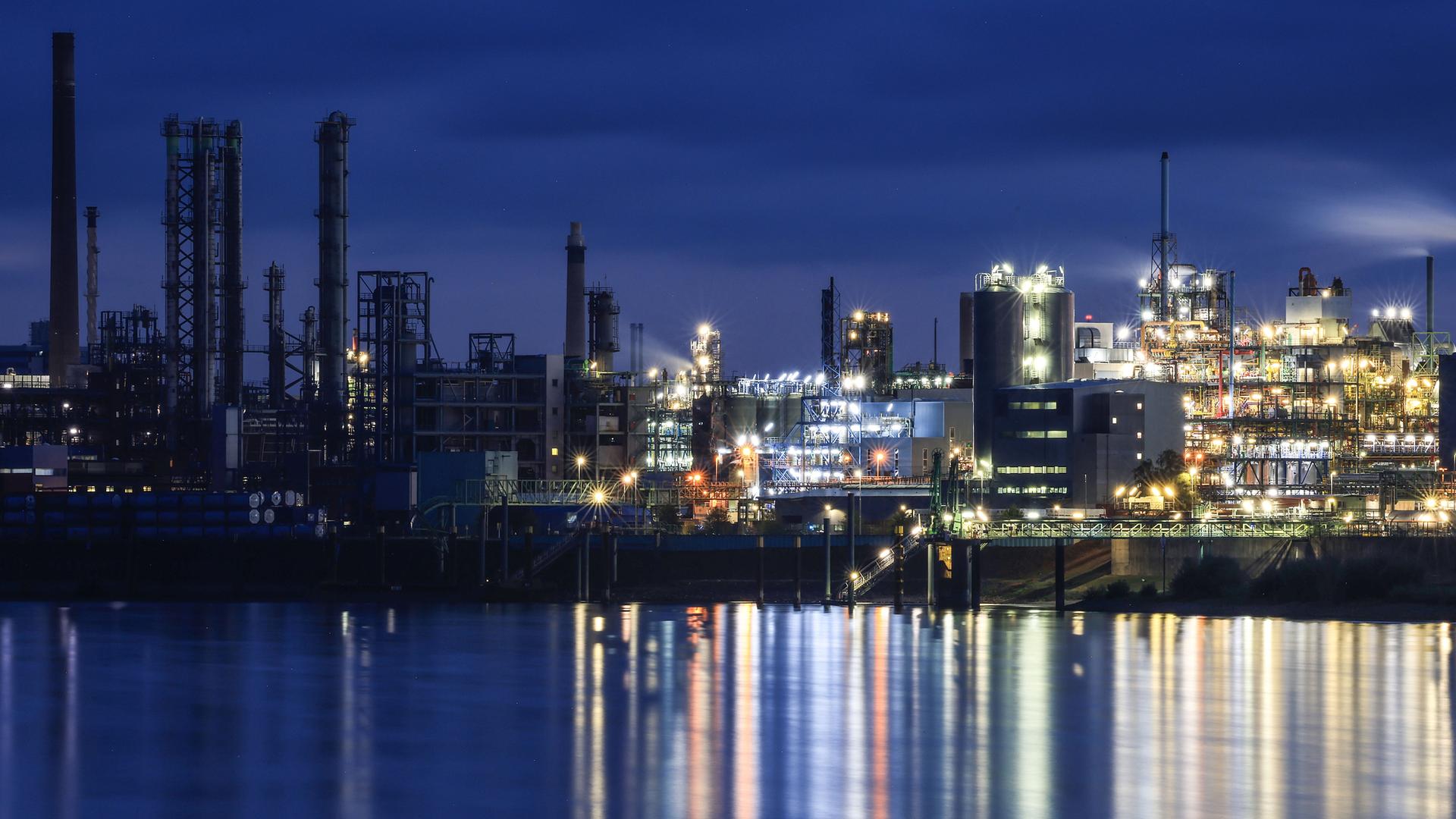 Lichter von Werksanlagen auf dem Chempark in Leverkusen spiegeln sich im Rhein.